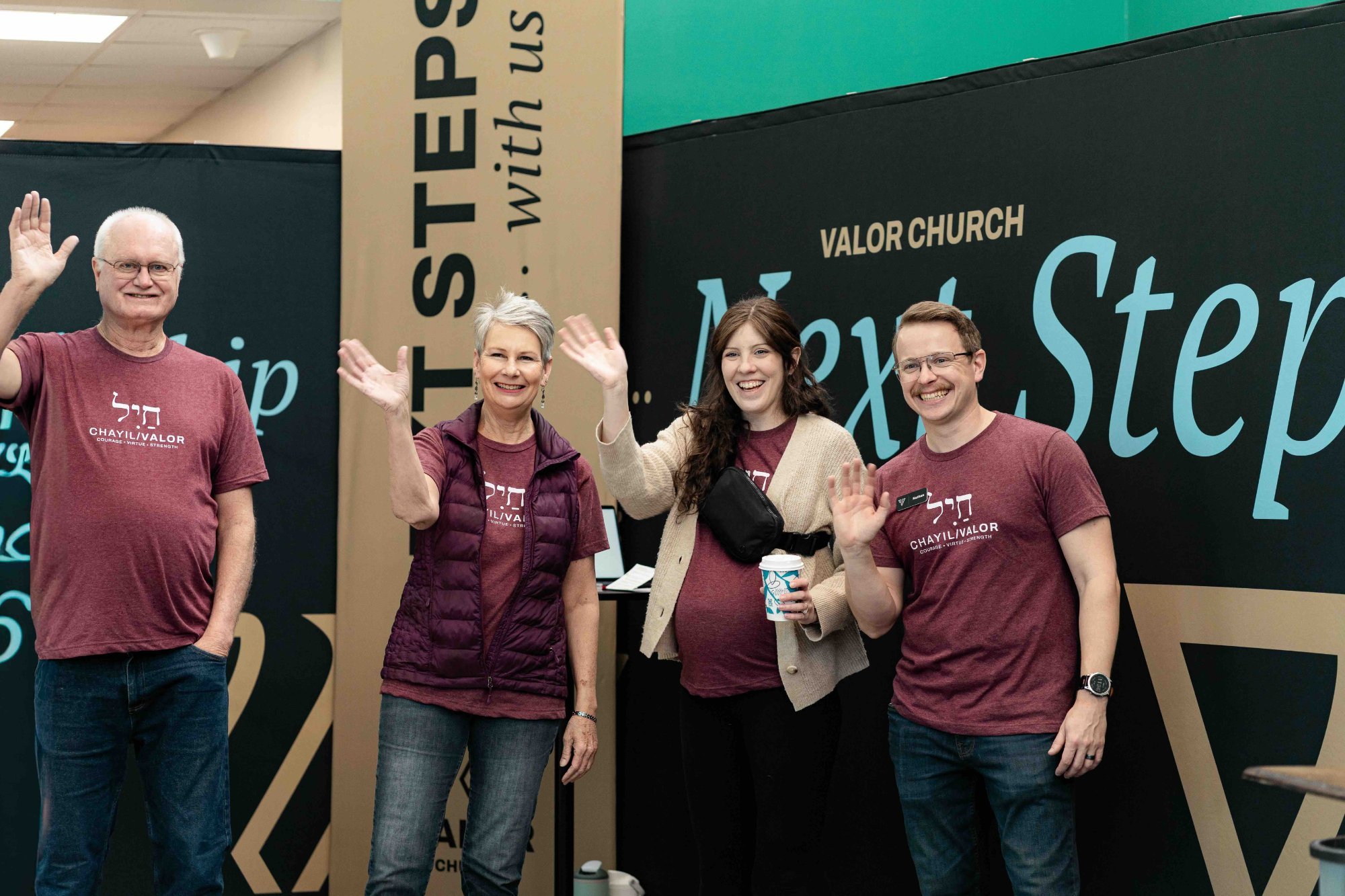 Valor Church serve team volunteers waving at the Next Steps table in Arvada